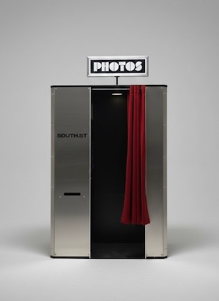 Brushed stainless steel photo booth with red curtain and PHOTOS sign