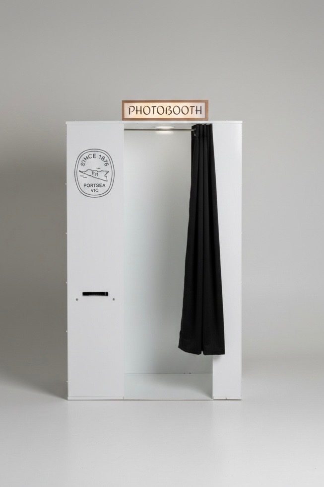 White photo booth finished with a venue's crest and a custom PHOTOBOOTH sign