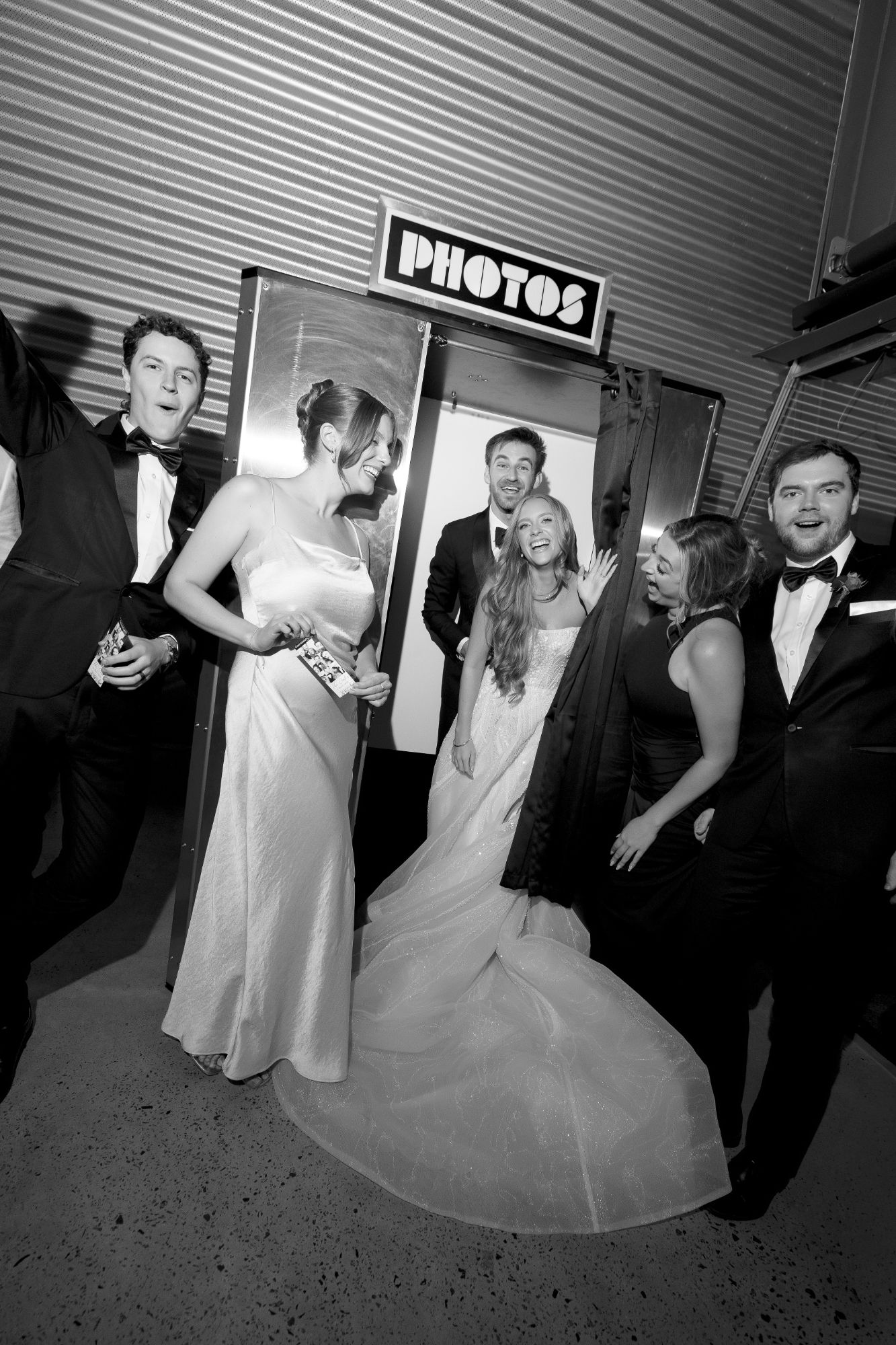 Wedding guests gathered around a stainless steel standing photo booth